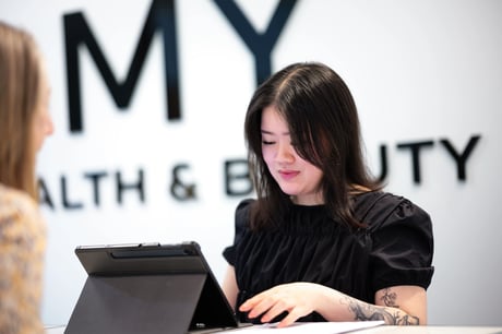 Woman with tattoos reviewing a tablet during a consultation at a health and beauty clinic.